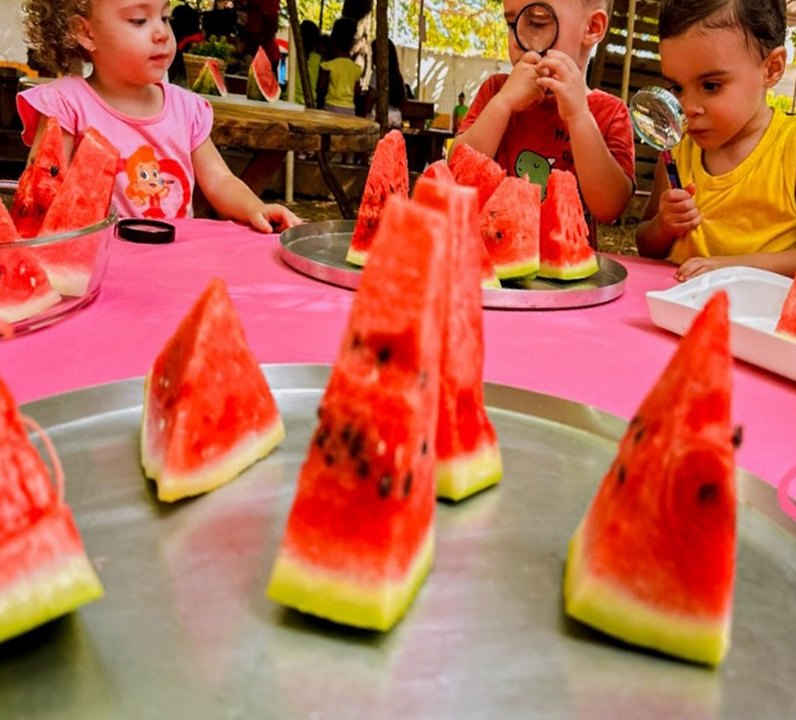Crianças do Recriar na mesa do lanche com melancia